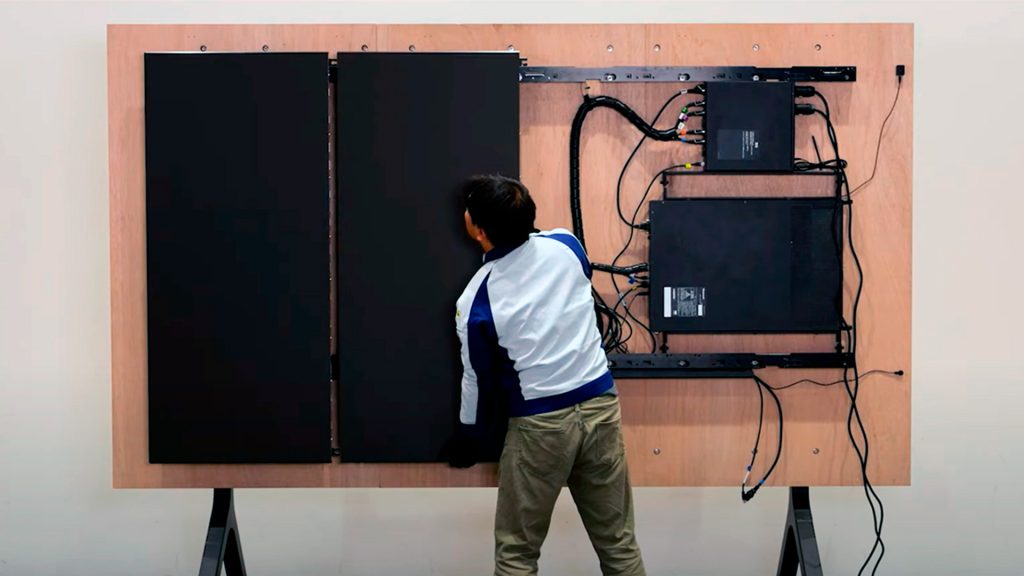 Technician installs panel number two of LED display on wall