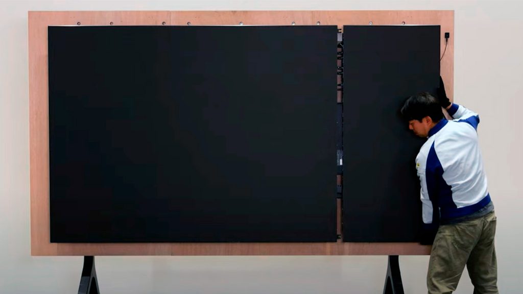 Technician installs last panel of LED wall