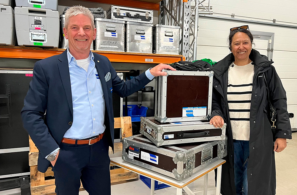 Mand og kvinde står med brugt AV-udstyr i transportkasser