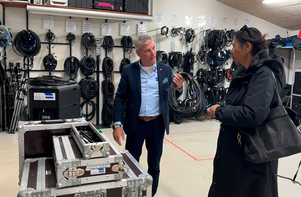 Mand og kvinde i samtale foran brugt AV-udstyr i transportkasser