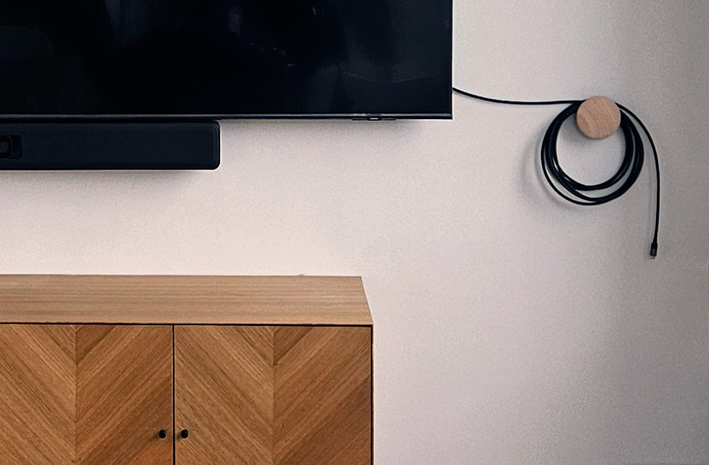 Skærm og videobar monteret på væg med et USB-C kabel hængende ved siden af